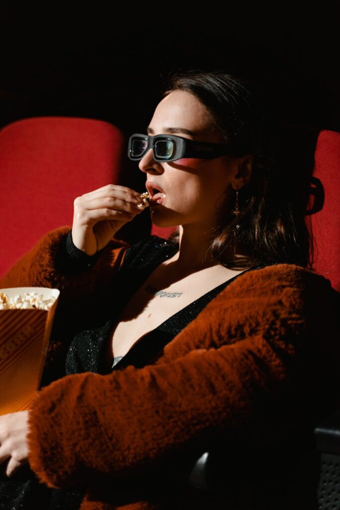 a woman in brown jacket eating popcorn